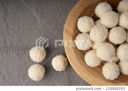 Coconut candies pile, coco ball. White truffle ball, indian ladoo or laddu with sweet cream and coco 128000293