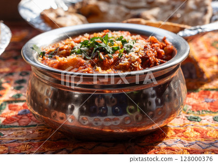 Lamb curry with tomatoes and fiery chili, traditional Indian Laal Maas served in a metal dish Lamb curry with tomatoes and fiery chili, traditional Indian Laal Maas served in a metal dish 128000376