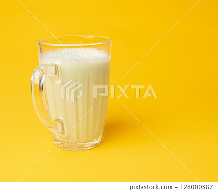 Vanilla milk shake in glass. Milkshake on yellow background, white whey protein smoothie 128000387