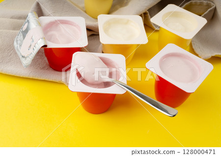 Yogurt cups set, pink and yellow fruit yoghurt in plastic pots, milk pudding container with spoon 128000471