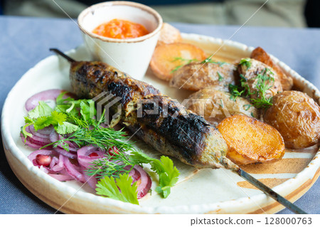 Georgian lula kebab plate. Bbq skewer, traditional barbecue dish with baked potatoes, sauce 128000763