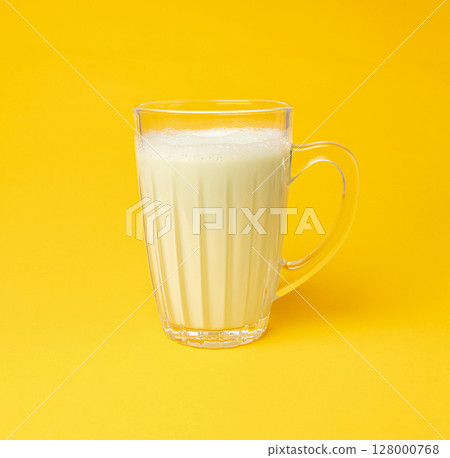 Vanilla milk shake in glass. Milkshake on yellow background, white whey protein smoothie 128000768