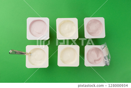 Yogurt cups set, pink and yellow fruit yoghurt in plastic pots, milk pudding container with spoon 128000934