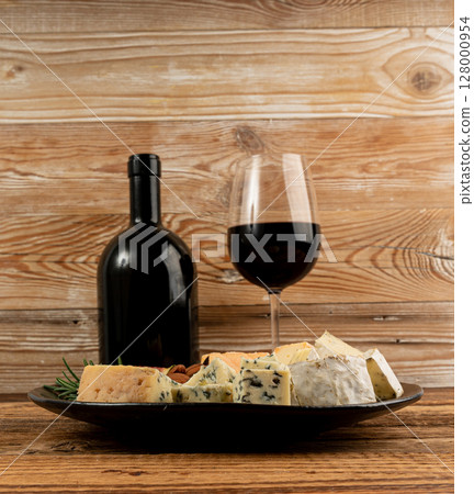 Cheese plate of color cheeses variety, yellow, white and blue gorgonzola platter with red wine glass 128000954