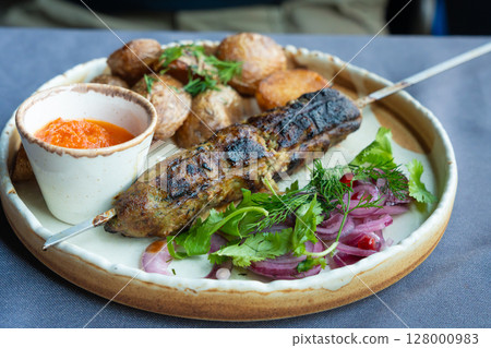 Georgian lula kebab plate. Bbq skewer, traditional barbecue dish with baked potatoes, sauce Georgian lula kebab plate. Bbq skewer, traditional barbecue dish with baked potatoes, sauce 128000983