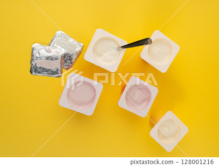 Yogurt cups set, pink and yellow fruit yoghurt in plastic pots, milk pudding container with spoon 128001216