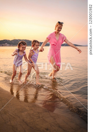 Joyful family moments by the serene beach at sunset 128001982