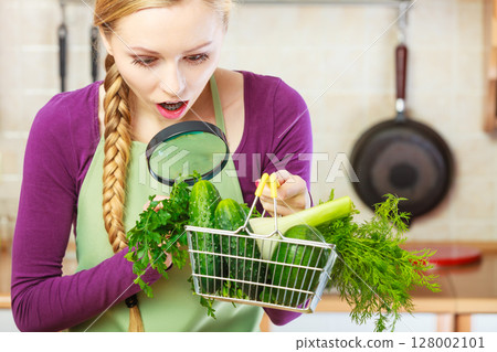 Woman looking through magnifier at vegetables basket 128002101