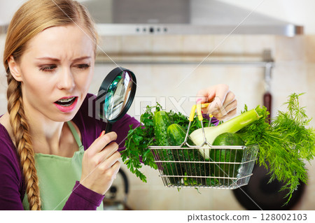 Woman looking through magnifier at vegetables basket Woman looking through magnifier at vegetables basket 128002103