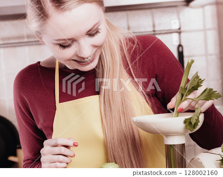 Woman in kitchen making vegetable smoothie juice Woman in kitchen making vegetable smoothie juice 128002160