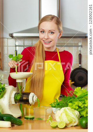 Woman in kitchen making vegetable smoothie juice Woman in kitchen making vegetable smoothie juice 128002161