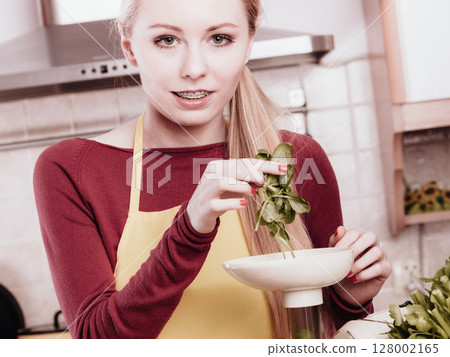 Woman in kitchen making vegetable smoothie juice 128002165