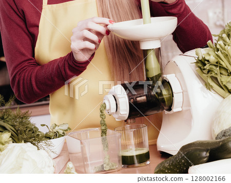 Woman in kitchen making vegetable smoothie juice 128002166