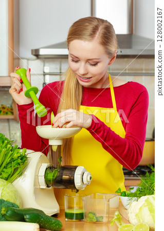 Woman in kitchen making vegetable smoothie juice 128002167