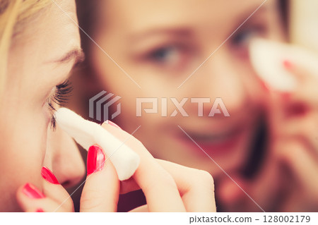 Woman using cotton pad to remove make up 128002179