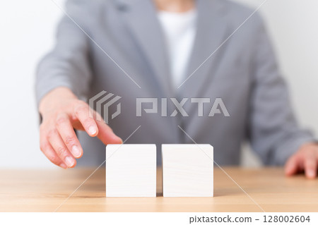 A middle-aged woman wearing a gray suit and a plain block 128002604