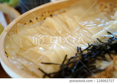 Glossy Cold Udon Noodles in a Bamboo Basket with Ice and Nori. Japanese Cuisine Close-Up Glossy Cold Udon Noodles in a Bamboo Basket with Ice and Nori. Japanese Cuisine Close-Up 128002727