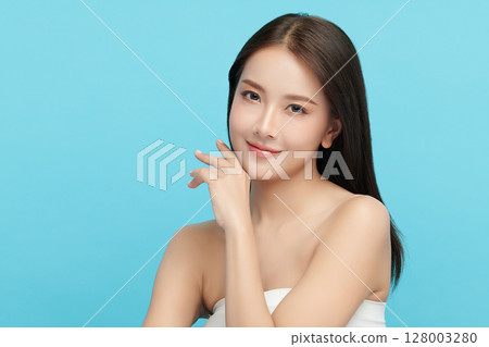 A beautiful young Asian woman with clean, fresh skin against a blue background. Skincare, facial treatment, cosmetology, beauty, and spa. An elegant portrait of an Asian woman. A beautiful young Asian woman with clean, fresh skin against a blue background. Skincare, facial treatment, cosmetology, beauty, and spa. An elegant portrait of an Asian woman. 128003280