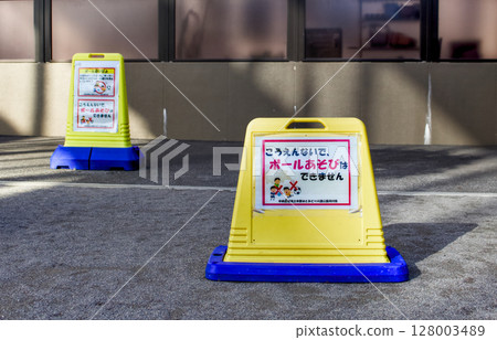 There is a sign posted in the park saying that ball games are not allowed. There is a sign posted in the park saying that ball games are not allowed. 128003489