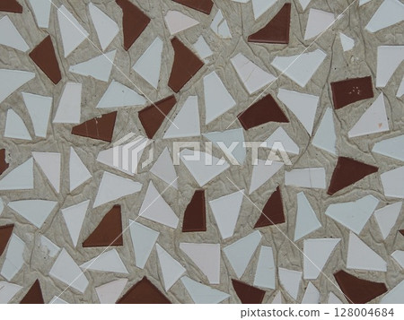 triangles of colored ceramics in cement mortar in wall texture as design element, close-up of triangle shaped ceramic tiles in concrete base as abstract texture 128004684