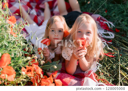Sister child girls on a plaid in a blooming poppy field, sunny summer day Sister child girls on a plaid in a blooming poppy field, sunny summer day 128005008
