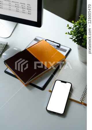 Modern workspace with a smartphone, notebooks, a clipboard, and a potted plant Modern workspace with a smartphone, notebooks, a clipboard, and a potted plant 128005470