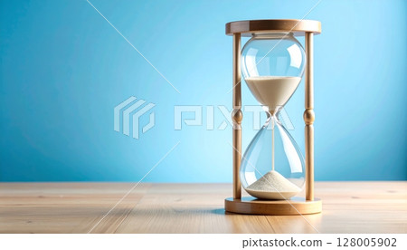 Antique sand timer on blue and black backgrounds 128005902