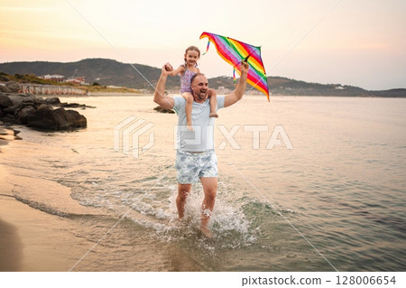 Joyful family moments at the beach with a colorful kite 128006654