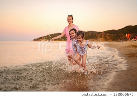 Joyful family moments splashing near the shore at sunset Joyful family moments splashing near the shore at sunset 128006675