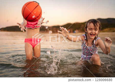 Family fun at the beach with kids splashing in the water 128006680