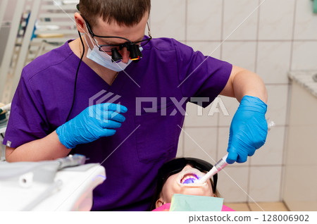 Dentist provides dental care to young patient in bright clinic during afternoon, ensuring comfort and maintaining dental hygiene for a healthy smile Dentist provides dental care to young patient in bright clinic during afternoon, ensuring comfort and maintaining dental hygiene for a healthy smile 128006902