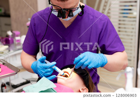 Skillful dentist performing a dental procedure on a training mannequin in a modern clinic with bright lighting Skillful dentist performing a dental procedure on a training mannequin in a modern clinic with bright lighting 128006903