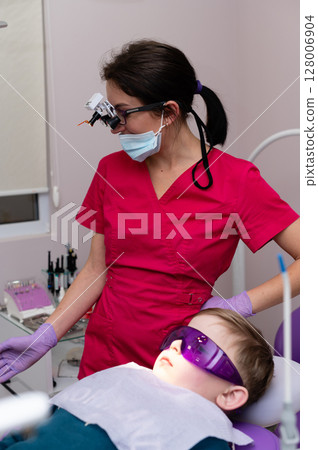 Pediatric dental checkup showcasing a caring orthodontist in vibrant scrubs assisting a young patient in a modern clinic Pediatric dental checkup showcasing a caring orthodontist in vibrant scrubs assisting a young patient in a modern clinic 128006904