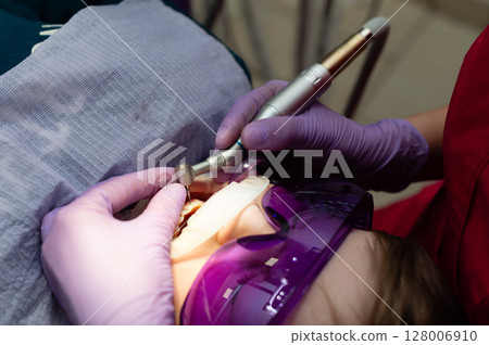 Dental professional performing advanced laser treatment on a patient in a modern clinic during a sunny afternoon 128006910