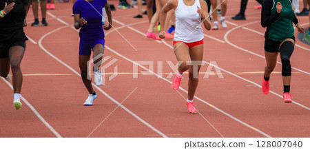 Female Runners Sprinting on a Track During Competitive Event Female Runners Sprinting on a Track During Competitive Event 128007040