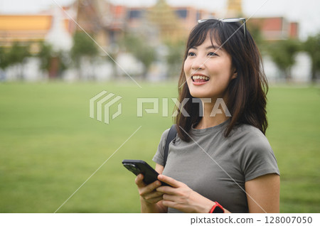 Happy southeast asian woman, solo blogger on world travel tour, uses smartphone map guide to explore Bangkok for local cultural tourism experience in Thailand, Asia 128007050
