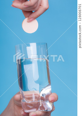 Person holding glass with water and effervescent tablet Person holding glass with water and effervescent tablet 128008701