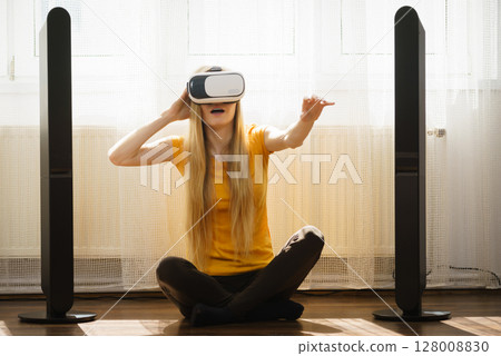 Girl wearing virtual reality goggles at home 128008830