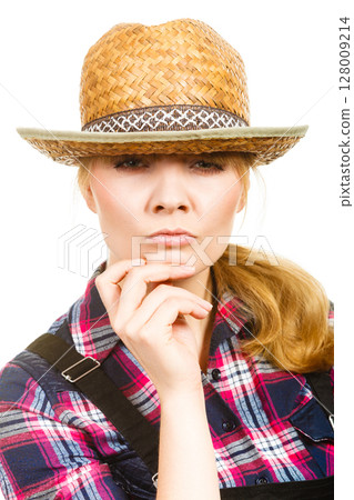 Thinking woman wearing sun hat and dungarees Thinking woman wearing sun hat and dungarees 128009214