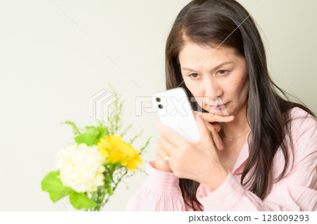 Senior woman worried while looking at her smartphone Senior woman worried while looking at her smartphone 128009293