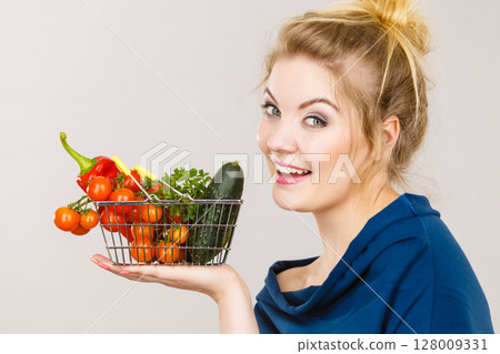 Woman holds shopping basket with vegetables Woman holds shopping basket with vegetables 128009331