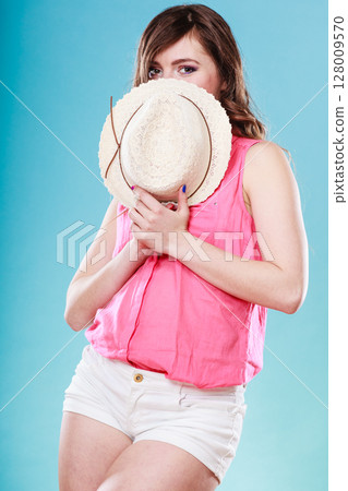 Cute girl holds summer straw hat covering her face 128009570