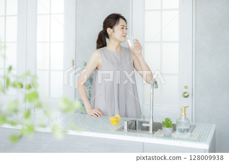 一個女人在廚房喝水 128009938