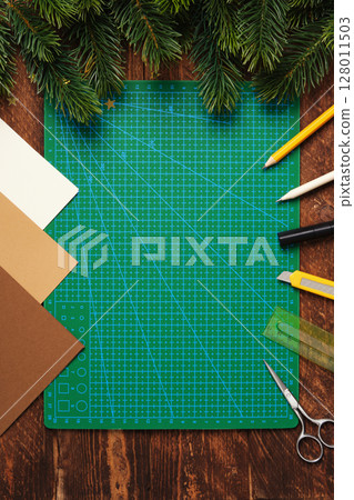 Workspace for paper crafts. Green cutting mat, colored paper, pencils, scissors, ruler. Space for your text. 128011503