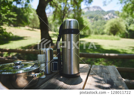 Picnic Set on Wooden Table in Lush Green Park on a Sunny Day Picnic Set on Wooden Table in Lush Green Park on a Sunny Day 128011722