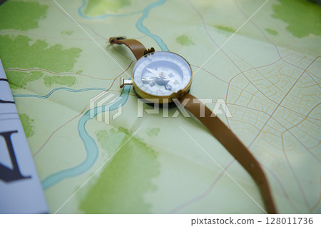Gold-Bordered Compass on Map Depicting River and Forest Details for Travel and Navigation 128011736