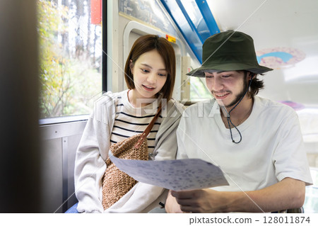 An inbound couple riding a cable car and looking at a map 128011874