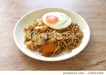 fried yakisoba Japanese noodles slice cabbage and carrot topping egg on plate   128012080