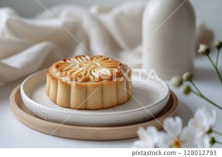 Traditional Chinese mooncake with delicate floral embossing on a white plate. Baked goods for celebrating the Mid-Autumn Festival in China or for fine dining presentations. 128012793