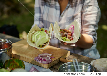 Person Holding Healthy Veggie Wraps Outdoors on a Picnic 128012838